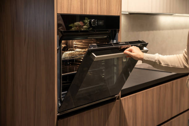 istock Hand opening a built-in oven in a modern wooden kitchen 2190987917