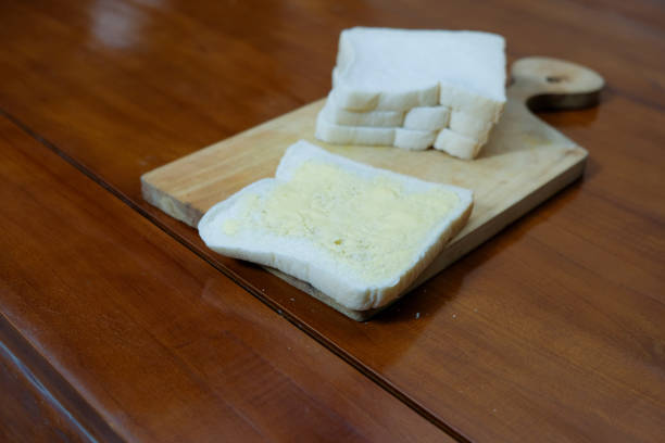 Fresh white bread with butter on wooden board in kitchen table, preparation breakfast, Copy space.