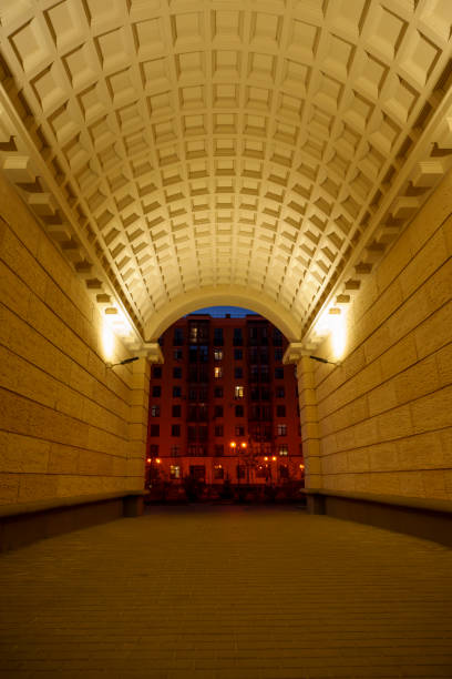 A striking architectural image showcasing a long, symmetrical corridor with a tiled ceiling and floor. The perspective creates an illusion of infinity, with rows of windows and light fixtures receding into the distance. The clean lines and repetitive elements emphasize the modern, minimalist design of the space.