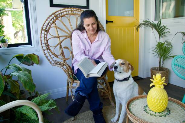 istock A woman holding a book while patting her dog 2190993233