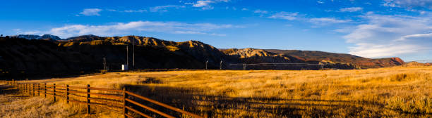 Rural Ranch Land and Mountains - Scenic view in golden hour light of ranch land, mountains, railroad track and irrigation equipment. Red rock canyons in background. Western Colorado along the Colorado River, USA.