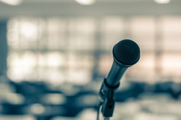 istock Microphone voice speaker in seminar classroom, lecture hall, town hall meeting or conference forum in educational business event for coaching host or teacher with audiences or students seats 2190997236