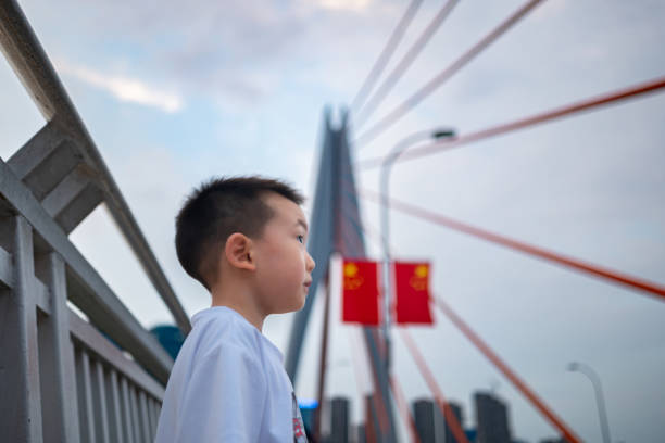 A boy on the bridge, with a modern city skyline, bridge, and wide river in the background, conveying a sense of freedom and joy