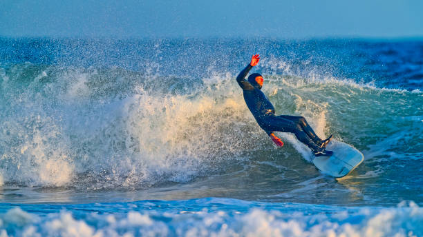 The Pacific Rim National Park in British Columbia on March 02, 2024: Young male surfer catching a wave at Pacific Rim National Park on Vancouver Island at sunset, British Columbia