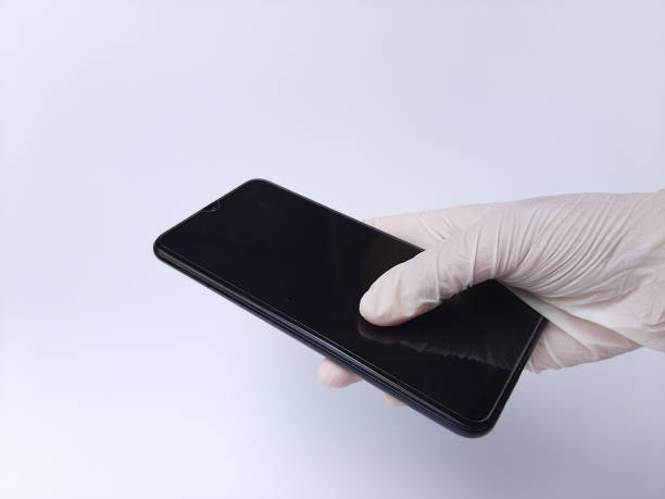 istock A hand with white latex glove holding a black mobile phone. Isolated on a white background 2191002766