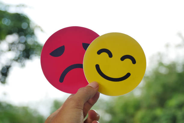 istock Hand holding a sad face card hiding behind a happy smiling face. Bipolar and depression concept, mental health concept, personality, mood swings 2191009454