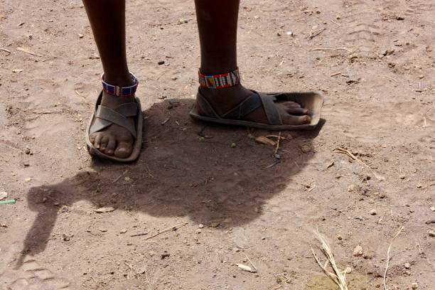 istock Barefoot with Sandals on Dusty Ground 2191013318