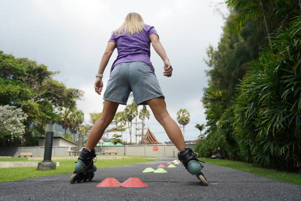 A woman is enjoying the activity of rollerblading along a scenic road that runs through a beautiful park setting.