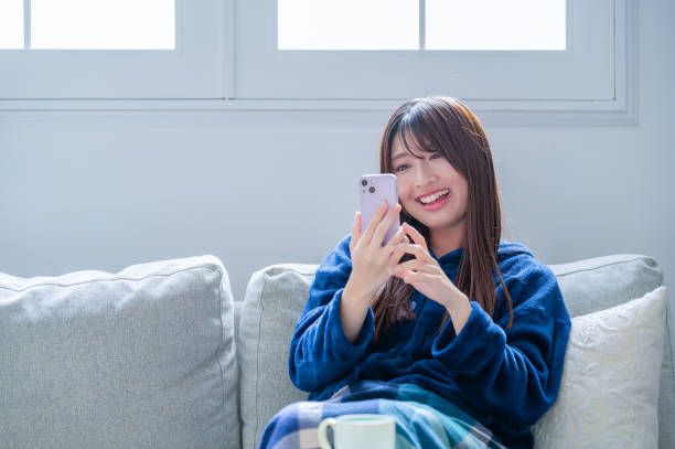 リビングでスマートフォンを見ている日本人女性 - 楽しい ストックフォトと画像