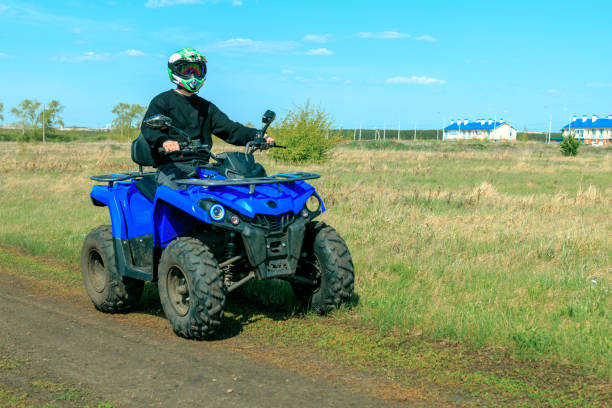Competitive quad biker kicking up a plume of sand while racing over a sand dune