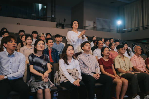 istock Asian woman standing and clapping cheering among crowd in auditorium 2191027134