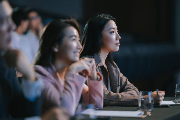 istock cheerful Asian panel judge watching stage performance competition in front of audience 2191027188