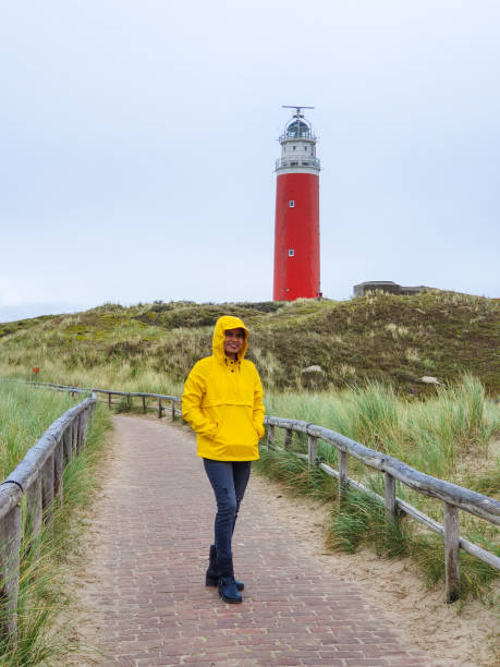 istock A wanderer in a yellow raincoat beside a striking red lighthouse on a cloudy day in Texel Netherland 2191027338