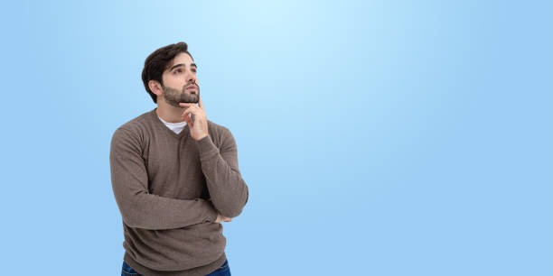 istock Thoughtful man wearing casual sweater, looking upwards with hand 2191028561