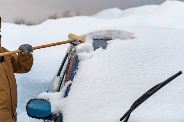 istock Young woman unloading snow from her car 2191028907