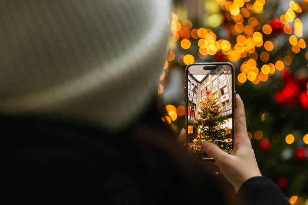 A young woman takes photos of a beautifully decorated Christmas tree at Berlin's Christmas market. The glowing holiday lights create a magical atmosphere