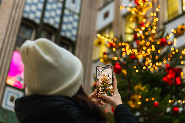 A young woman takes photos of a beautifully decorated Christmas tree at Berlin's Christmas market. The glowing holiday lights create a magical atmosphere