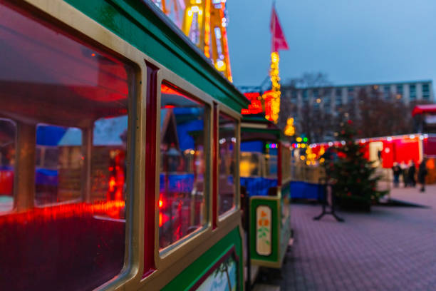 A vibrant green miniature train at a Christmas market in Berlin, illuminated with festive lights and surrounded by holiday decorations. A charming and nostalgic attraction for children and families during the winter holiday season