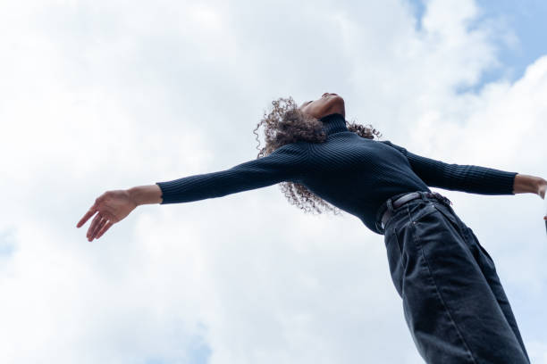 istock Low Angle View of a Woman Stretching Arms Under a Cloudy Sky 2191034236