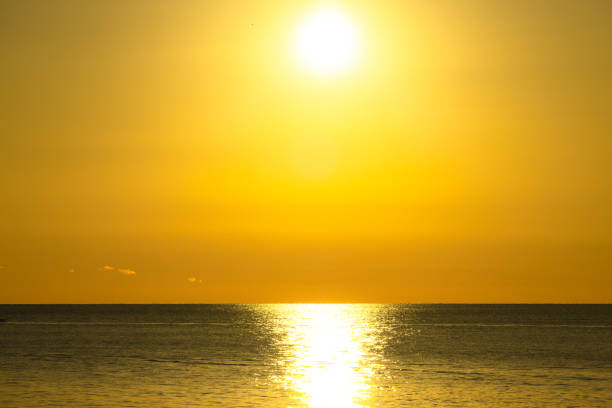 The sun's rays are reflected on the sea. The sky is burning. Orange sun and fantastic sunset over the sea. Beautiful landscape with golden sun, sea and sunset. Big shining sun
