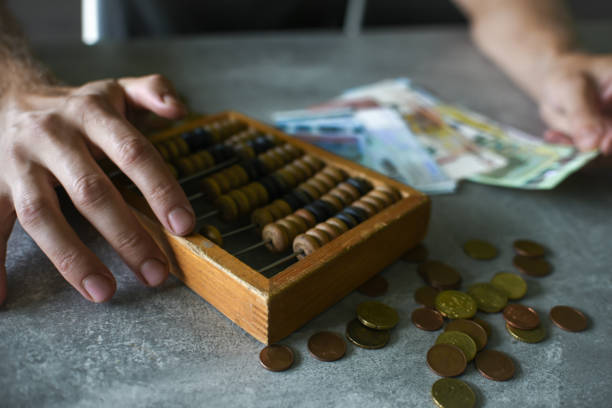 Title: Man counting money on gray table with abacus and euro banknotes