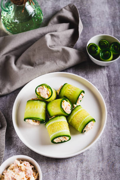 istock Cucumber rolls with fish salad on a plate on the table vertical view 2191035987