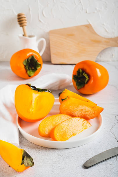 Sliced ripe fresh persimmon on a plate on a table vertical view
