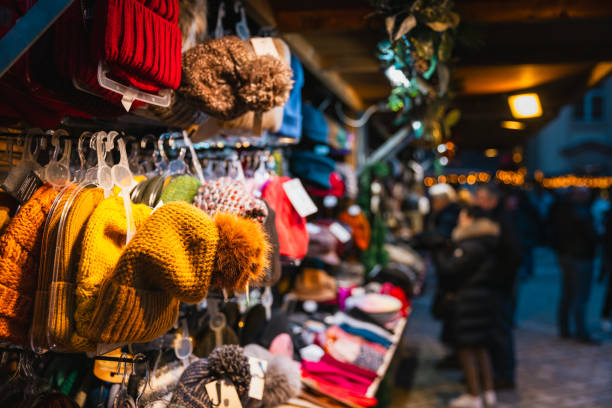 Row of little handmade souvenir felt boots decorated with vibrant embroidered national chuvash patterns and colorful ribbons. Traditional folk crafts hanging from a chain in market setting.