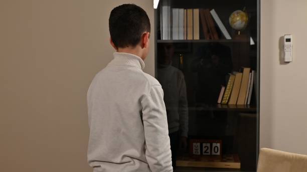 istock Young boy looking at bookshelf with reflection and date displayed 2191036306