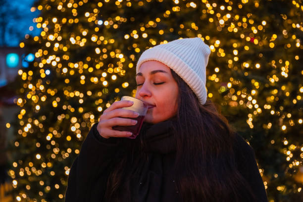 A young woman radiates happiness as she enjoys a warm drink at a Berlin Christmas market. Behind her, a beautifully lit Christmas tree and the iconic Berlin TV Tower create a magical evening backdrop. This photo captures the warmth and festive spirit of the holiday season in the heart of Berlin.