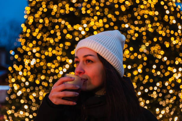 A young woman radiates happiness as she enjoys a warm drink at a Berlin Christmas market. Behind her, a beautifully lit Christmas tree and the iconic Berlin TV Tower create a magical evening backdrop. This photo captures the warmth and festive spirit of the holiday season in the heart of Berlin.