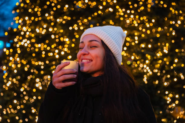 A young woman radiates happiness as she enjoys a warm drink at a Berlin Christmas market. Behind her, a beautifully lit Christmas tree and the iconic Berlin TV Tower create a magical evening backdrop. This photo captures the warmth and festive spirit of the holiday season in the heart of Berlin.