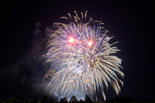 istock A night sky filled with vibrant white and red fireworks, bursting in various sizes, creating a dazzling visual effect against the dark background. 2191039231