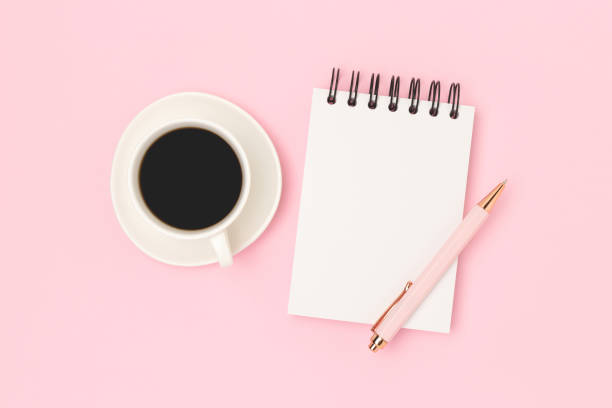 istock Cup of black coffee and empty notepad mockup on a pink background. 2191043704