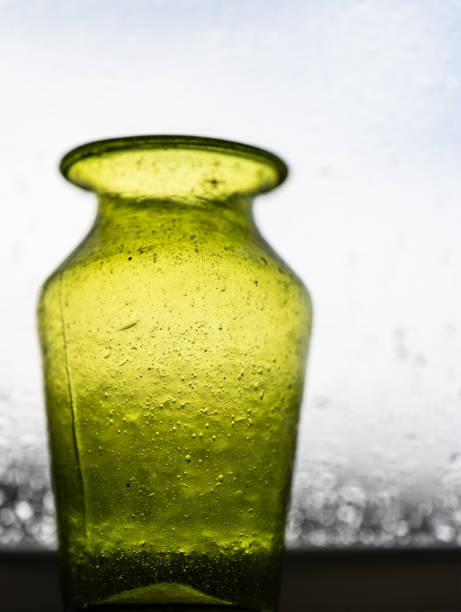 istock Green hand made glass vase in a window.. 2191044542