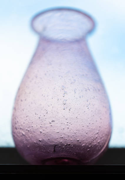Purple hand made glass vase in a window.