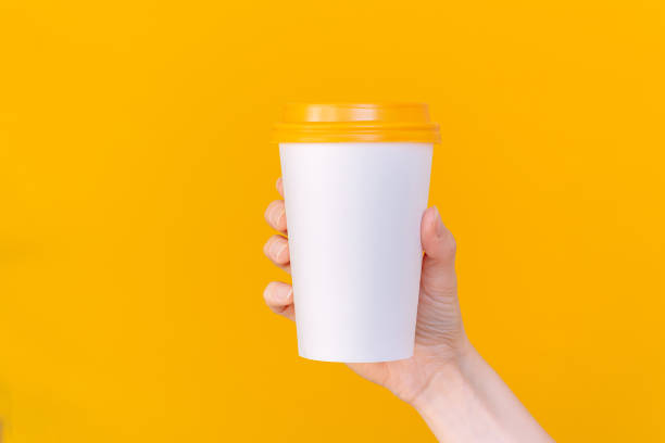 istock A woman's hand holding a white paper coffee cup with an orange lid. Empty space. Mock up. 2191048637
