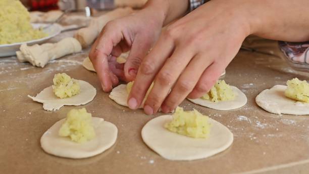 istock Hands making dumplings with potato filling on dough placed on a wooden surface 2191049529