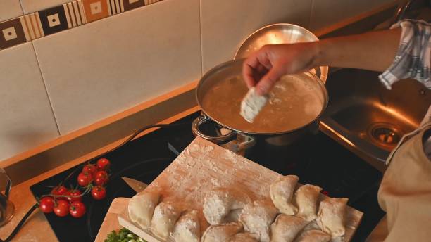 istock Hand Preparing Dumplings Over A Stove in a Cozy Kitchen Setting 2191049606