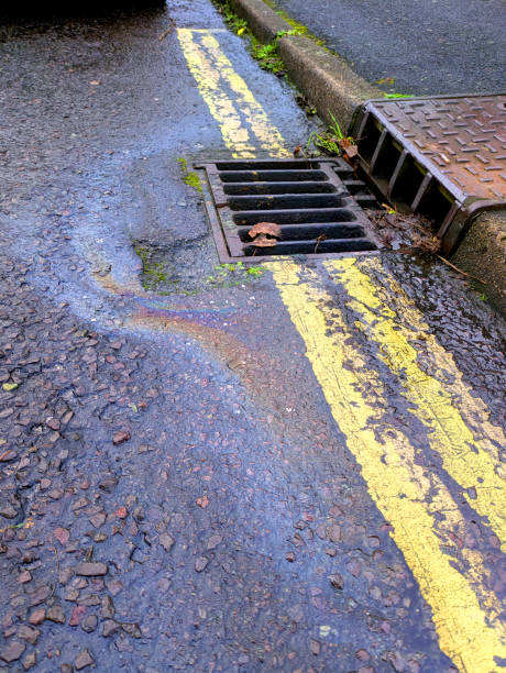 istock Oil Petrol Environmental Rainbow Leak Running Down a Drain 2191054301