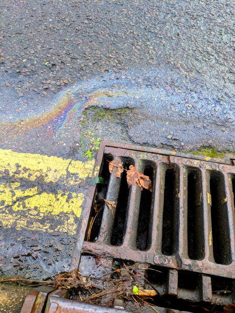 istock Oil Petrol Environmental Rainbow Leak Running Down a Drain 2191054687
