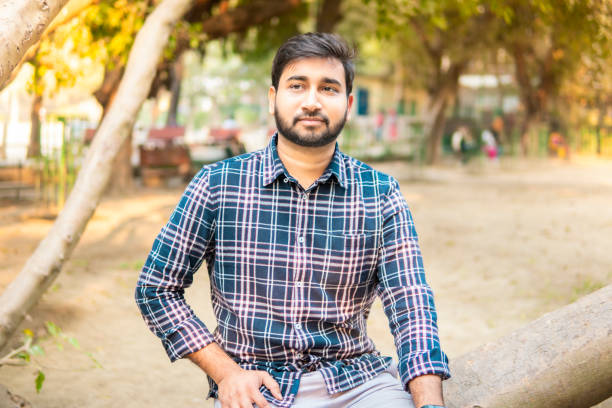 istock Relaxed indian young man sitting on a fallen tree and contemplating in fresh air. 2191055435