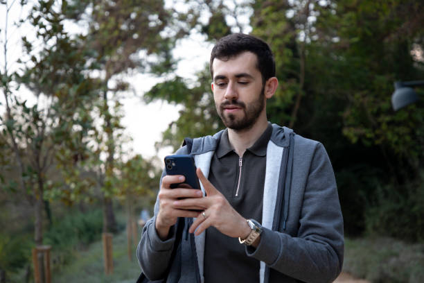istock Young man looking at his phone while walking in nature 2191055562
