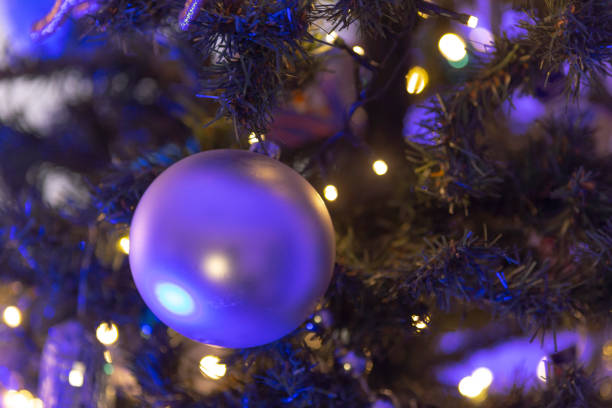 Amidst the quiet of night, a captivating orb of purple lights emerges as a luminous landmark against the dark canvas of the sky. This photograph captures the magical essence of the holiday season through a magnificent display of lights, arranged meticulously to form a gigantic glowing sphere. This radiant structure, a modern interpretation of a festive bauble, illuminates the surrounding area with a warm, inviting glow, symbolizing hope and joy. The lights reflect the spirit of the season, inviting passersby to pause and bask in the enchanting atmosphere created by this urban installation.