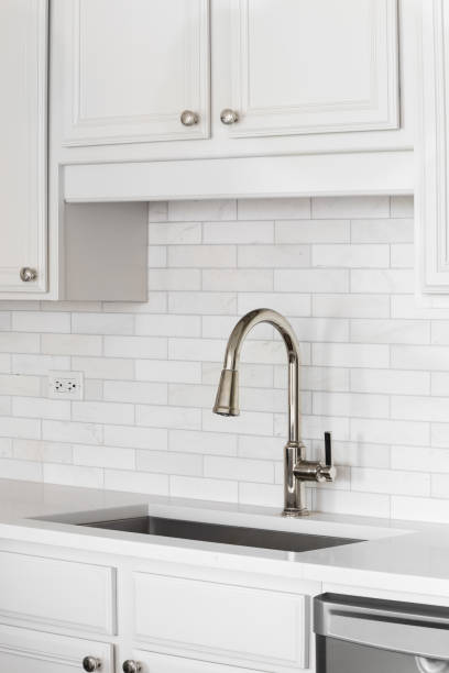 istock A kitchen sink detail with a brushed gold faucet and subway tile backsplash. 2191057256
