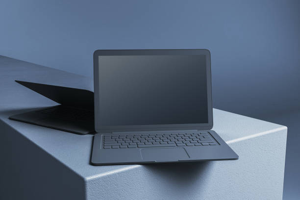istock Modern laptops with open screens displayed on a textured surface in a minimalistic composition. 3D Rendering 2191058811