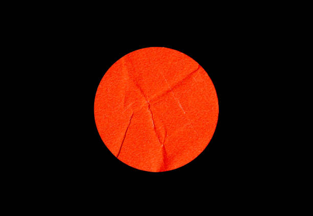 Orange adhesive glued round paper sticker label isolated on black background