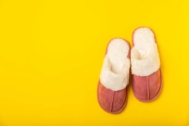 Hairy men's legs in pink felt slippers.