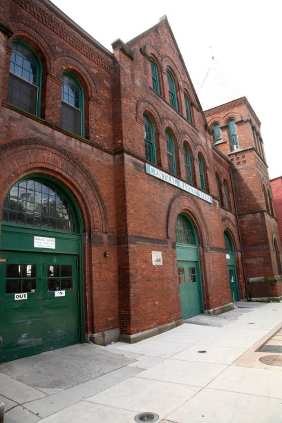 Built in the  Romanesque Revival style in 1888 it features wide red brick arches housing large green wooden doors, arched windows and central pyramidal roof above and one of two pyramidal towers above