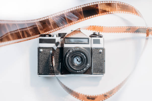 istock Vintage film camera with roll film strip on white table 2191072108